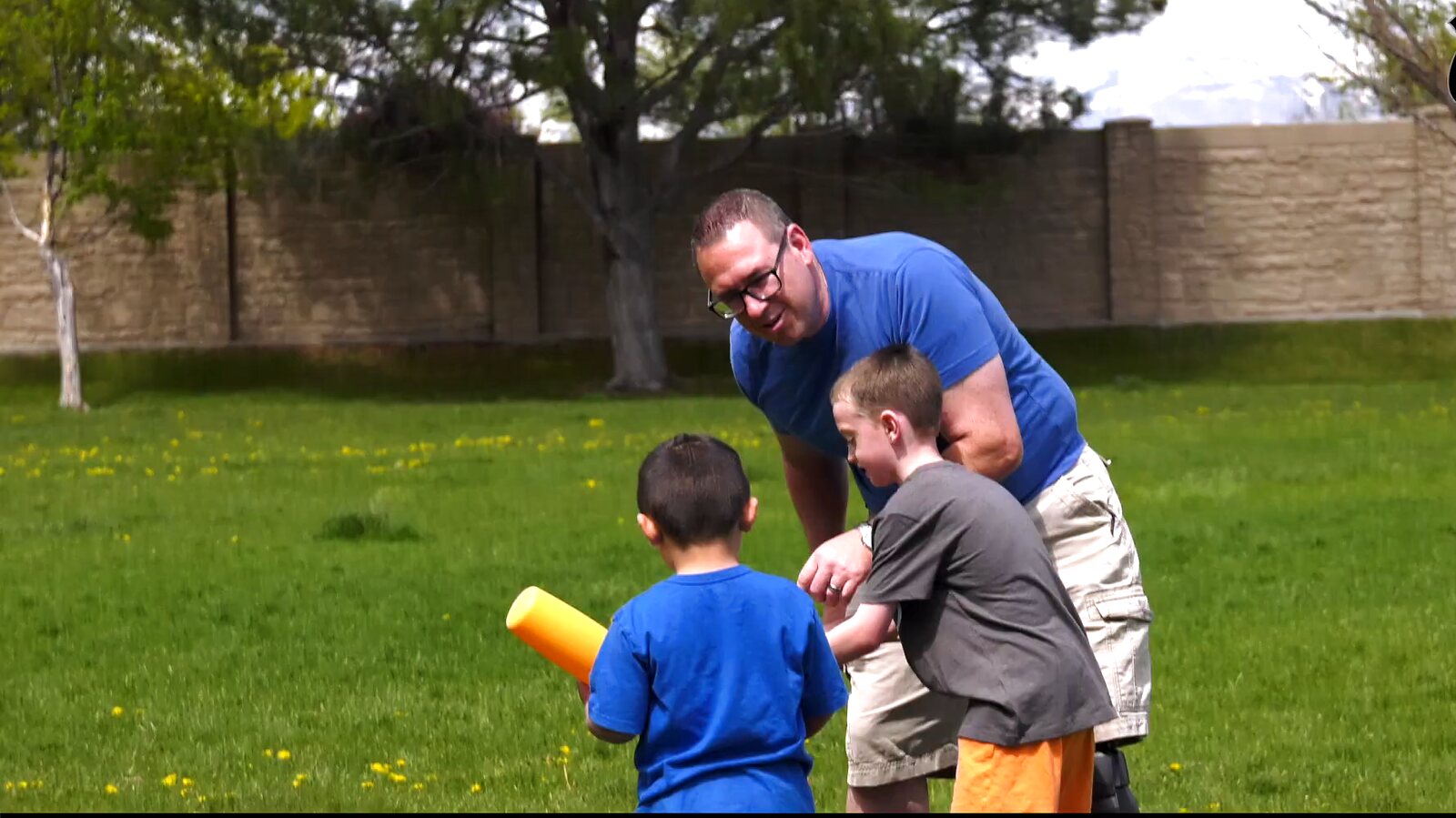 An injured officer playing ball with his sons on a spring lawn